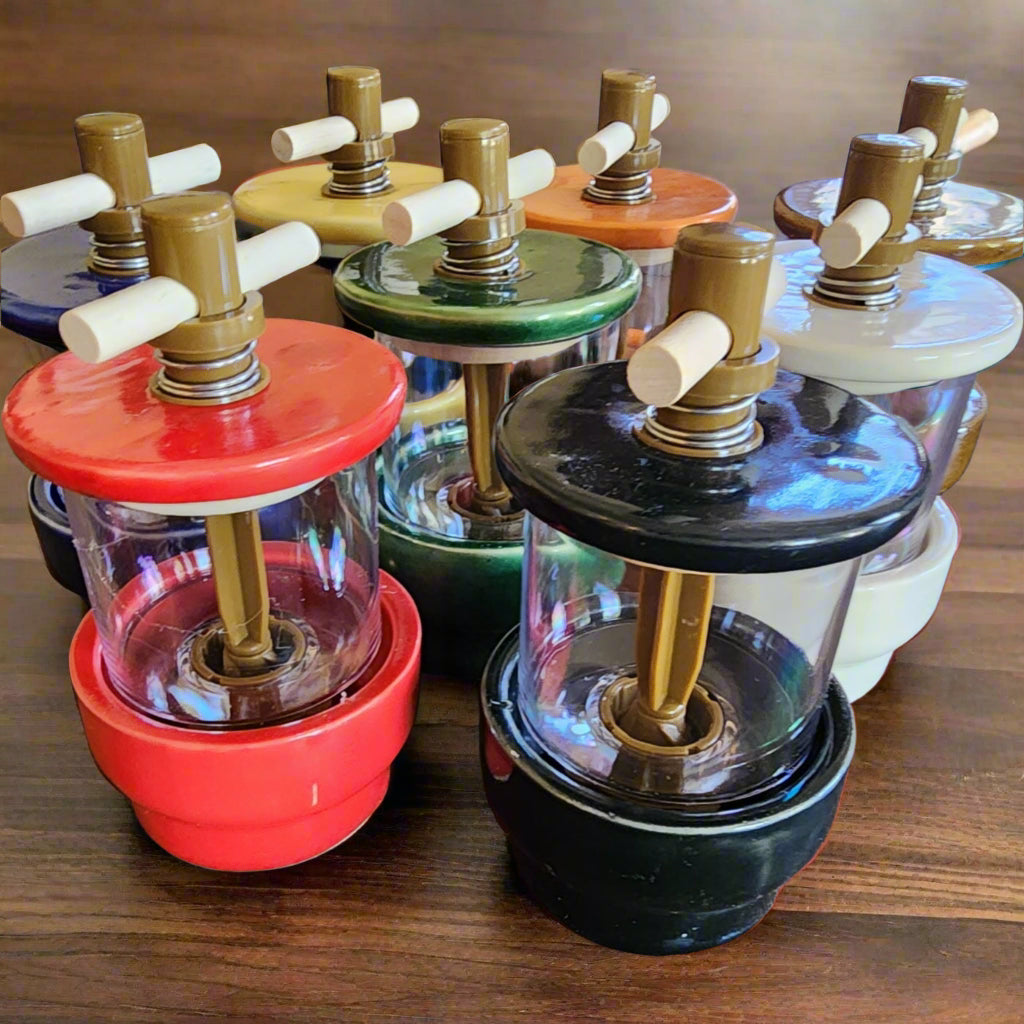 Herb grinders in assorted colors red, black, blue, green, yellow, orange, white and gold by Pako Lazo Pottery.